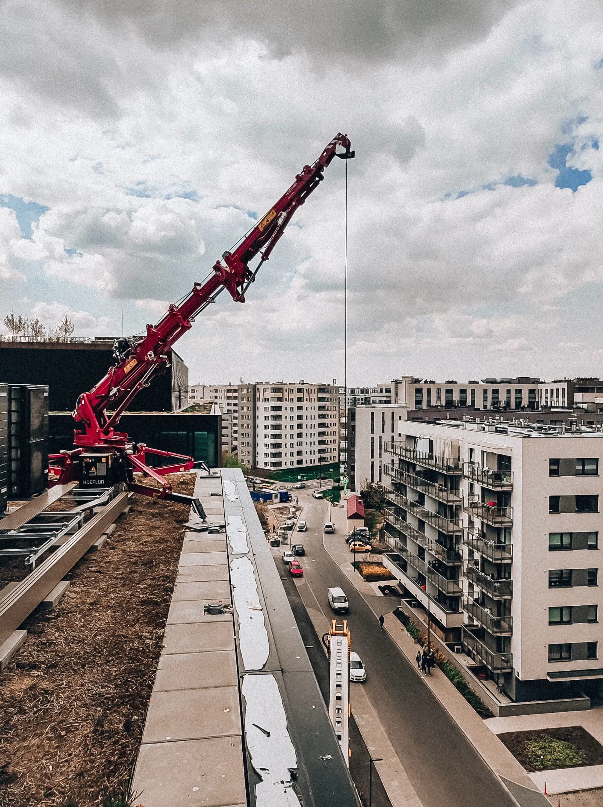 Hoeflon crane lifting something off a building's roof.