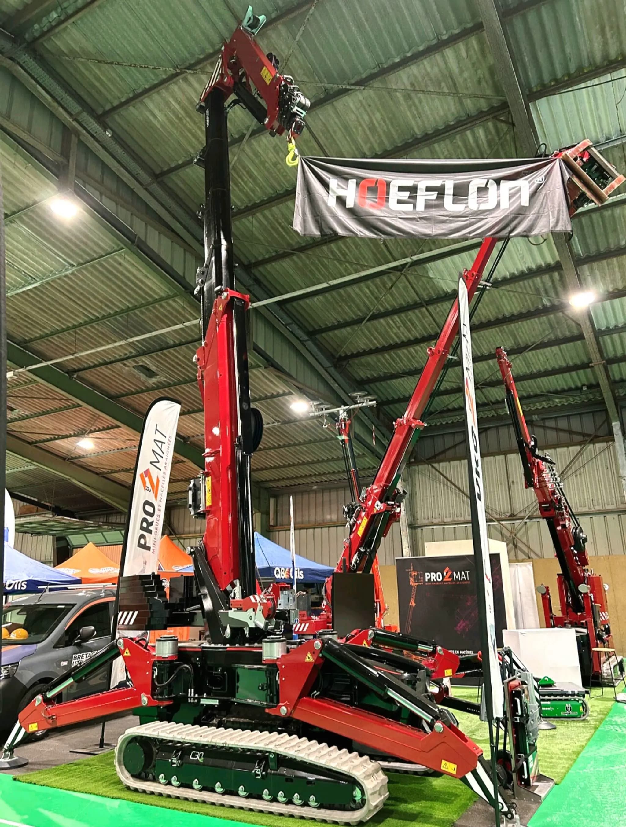 Hoeflon crane at trade show booth with banner.