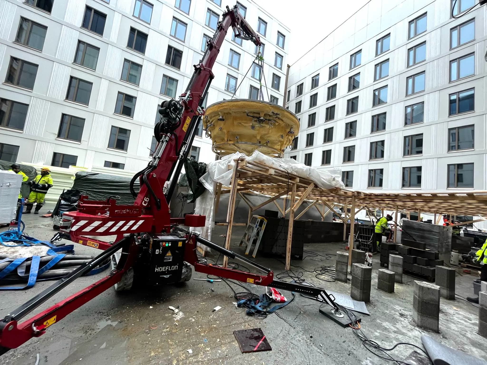 Hoeflon crane lifting object at construction site.