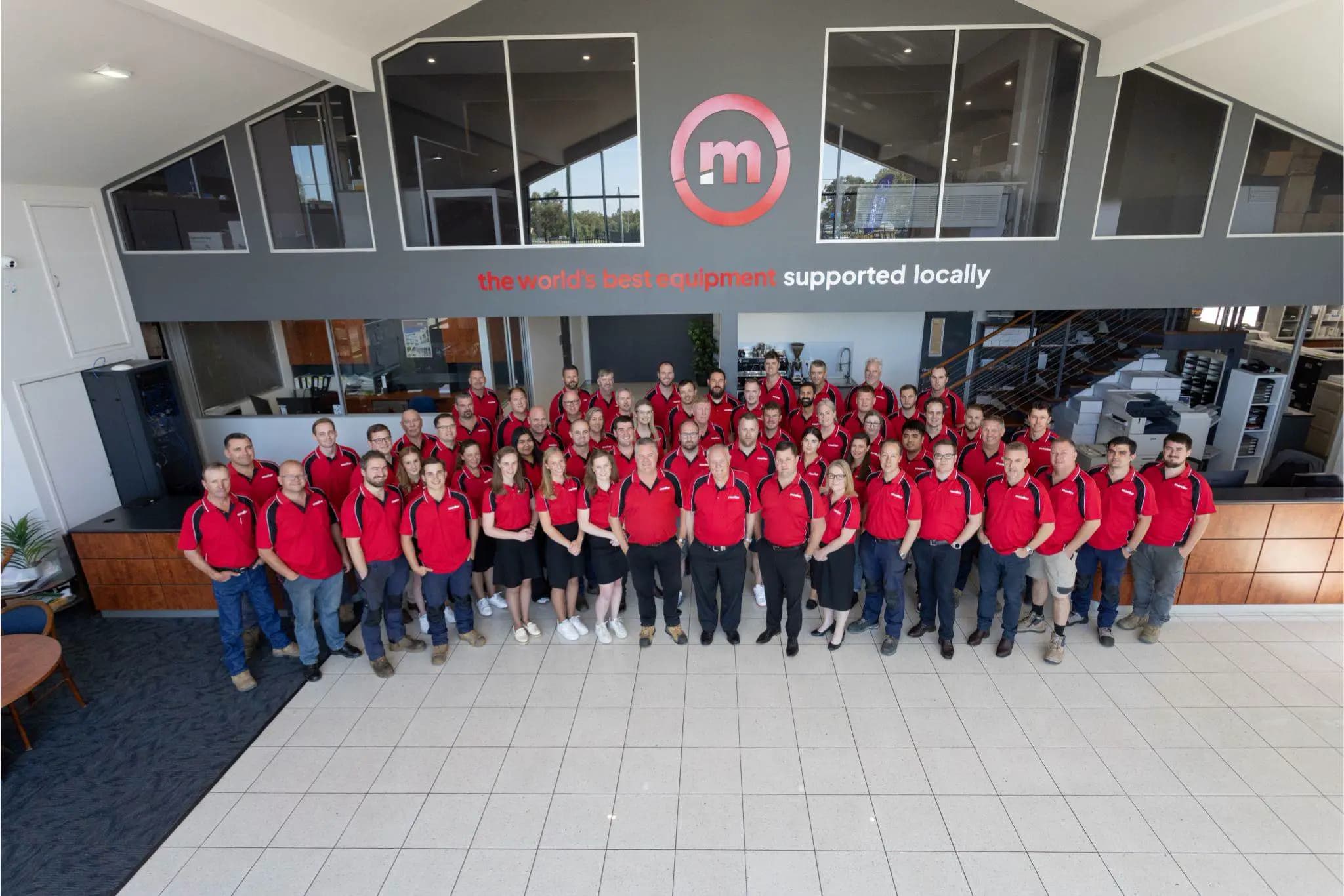Group photo of the Monitor team in red shirts in an office space.