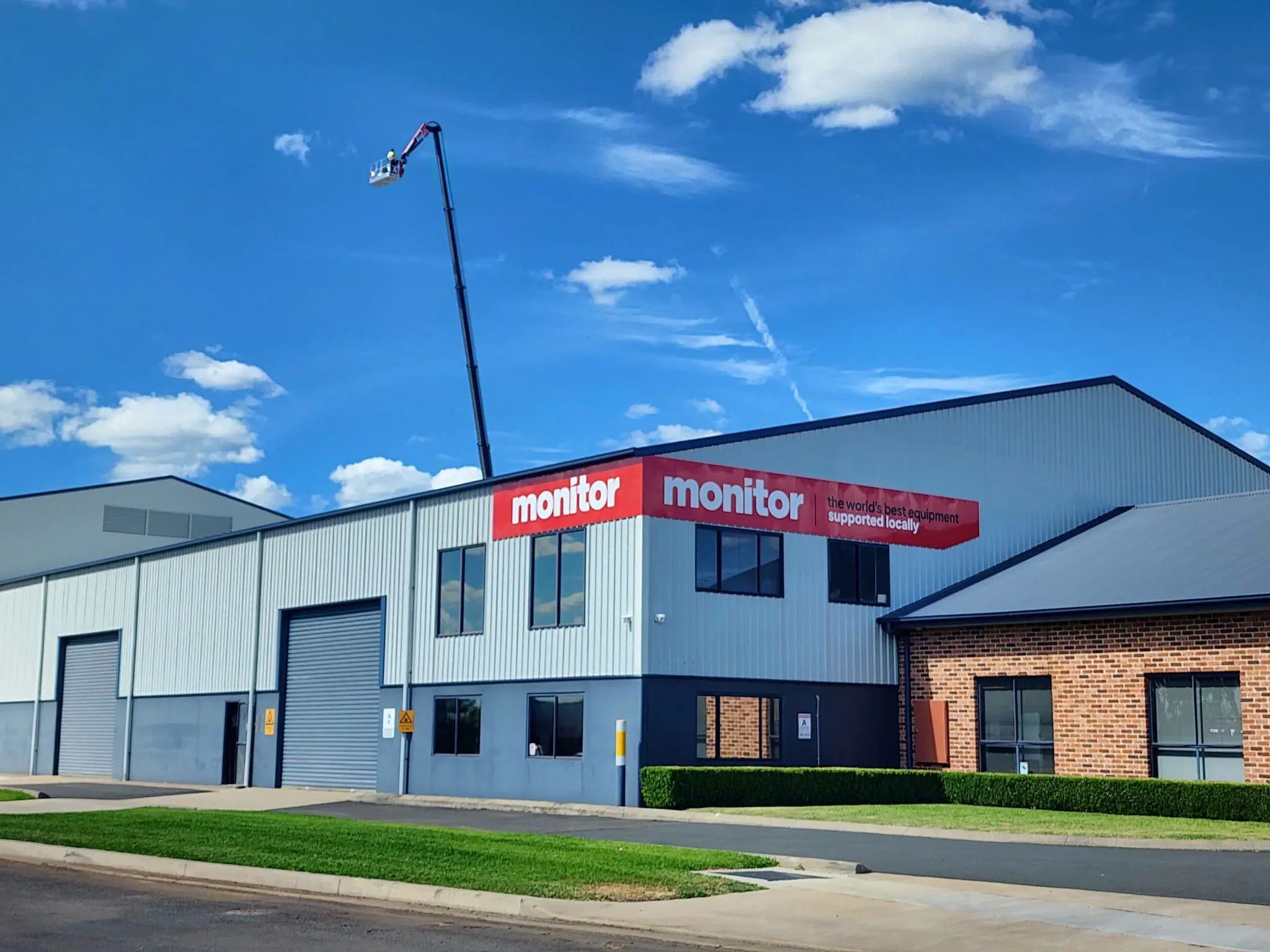 Aerial lift at a building with a monitor sign next to it.