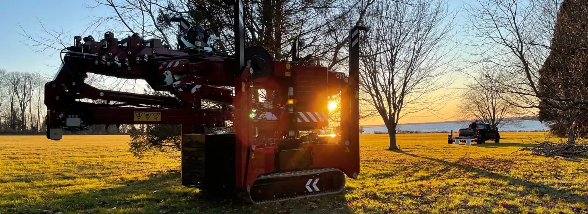 Hoeflon crane in the sun, with a truck in the background and trees around.