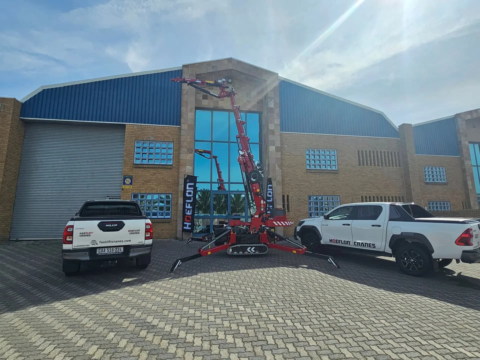 Dealer Fastlit Cranes met een kraan voor het pand en 2 auto's