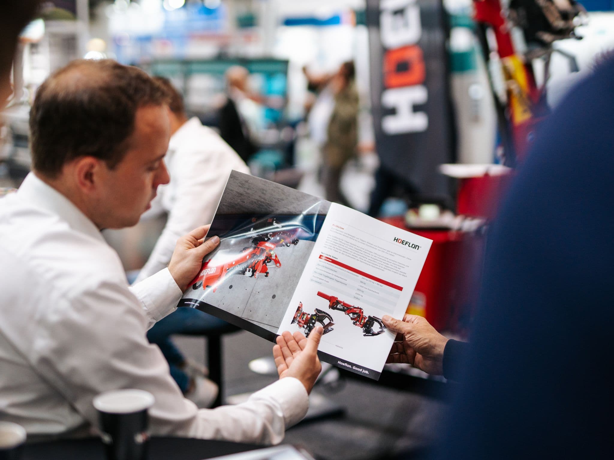 Person reviewing a Hoeflon brochure at a trade show.