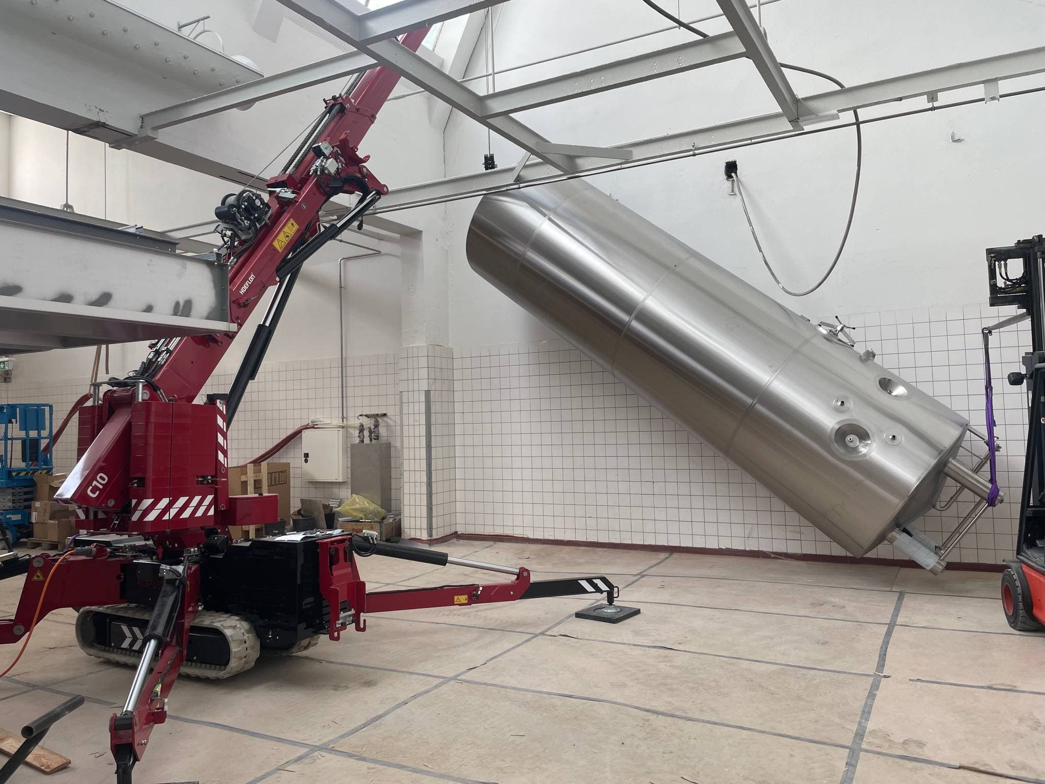 Hoeflon C10 lifting a large cylinder in a factory hall.