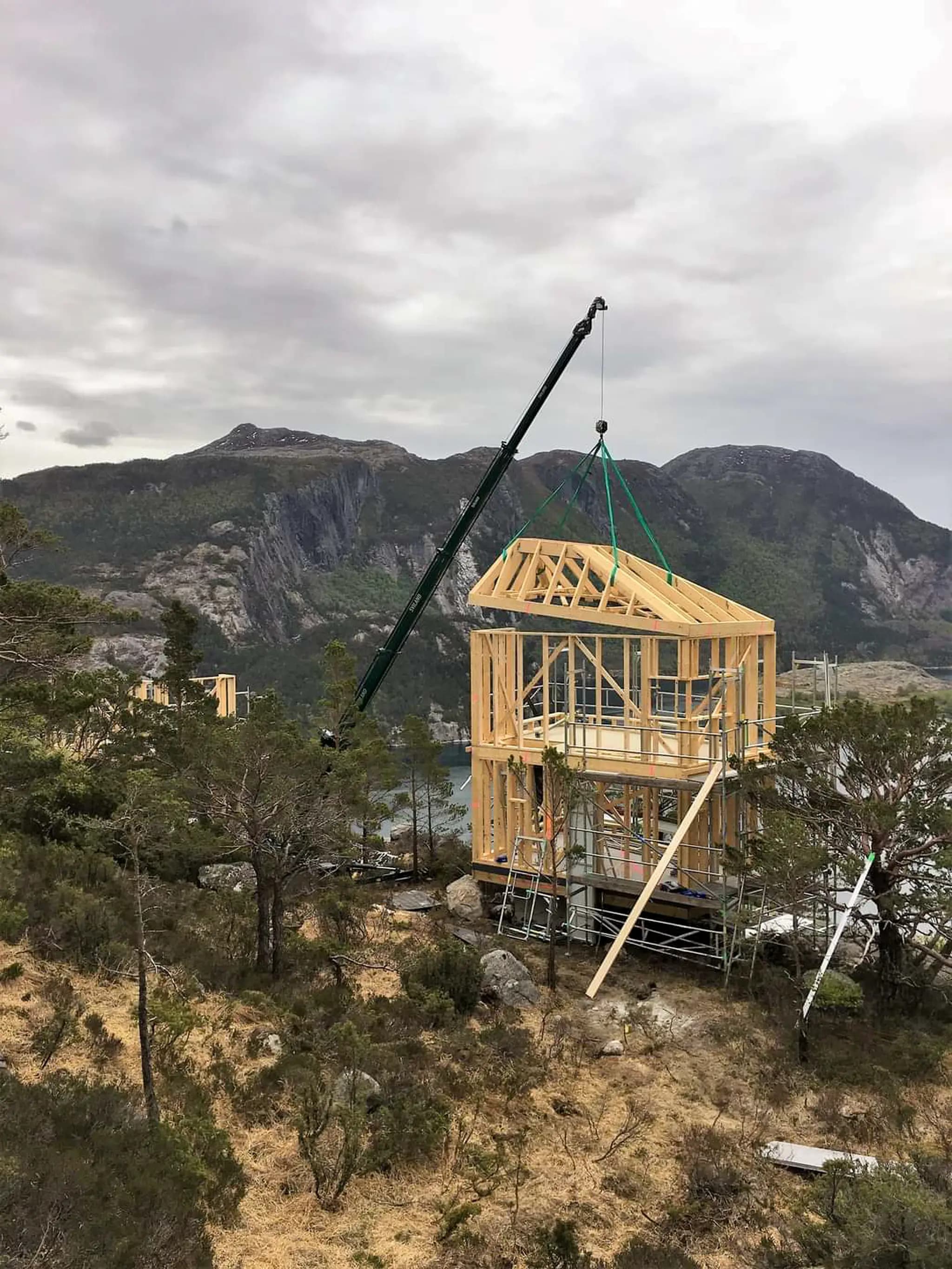 Hoeflon C6e lifting a wooden frame in Norway with mountains in the background.