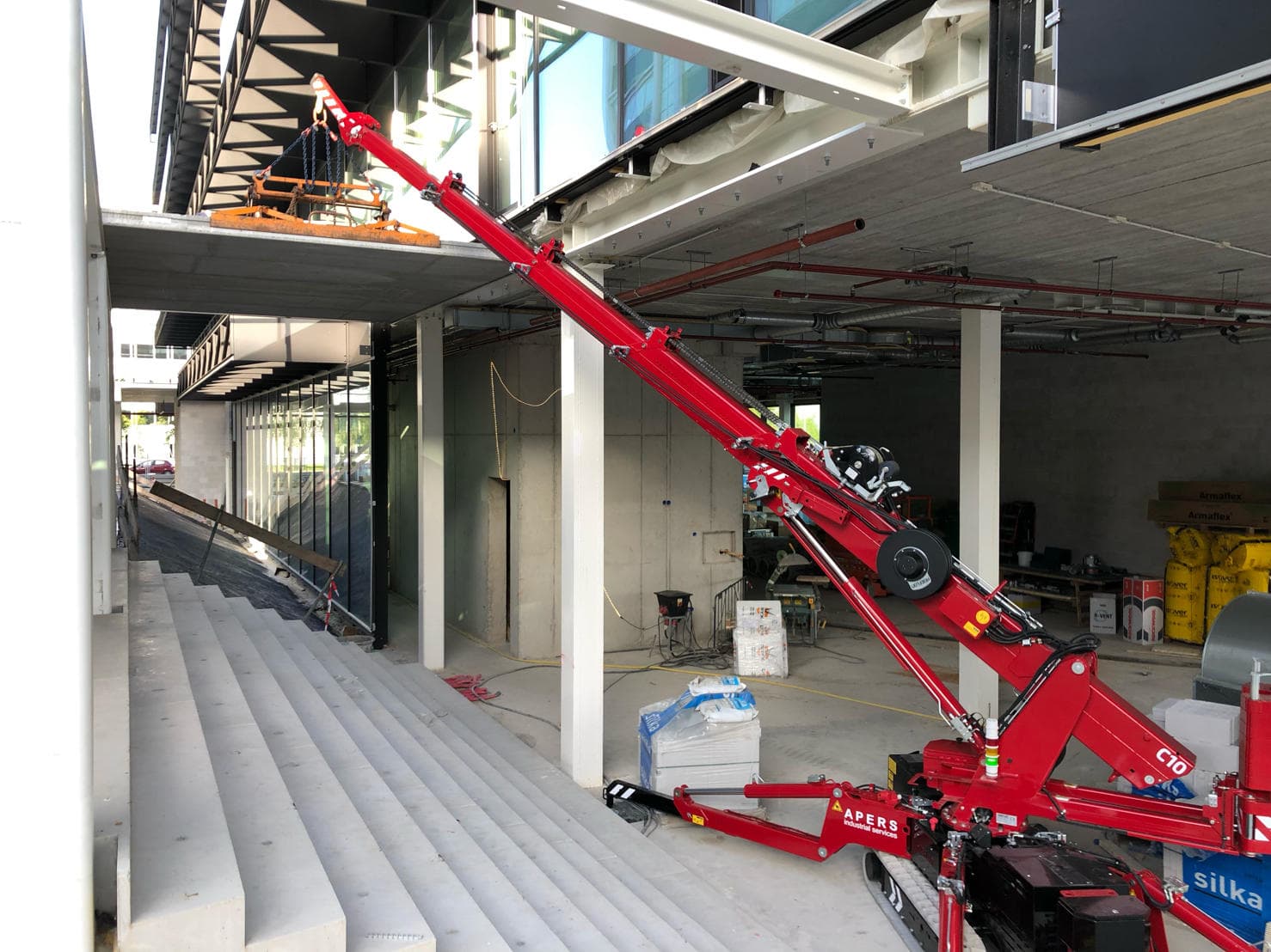 Hoeflon hijskraan aan het werk in een gebouw.
