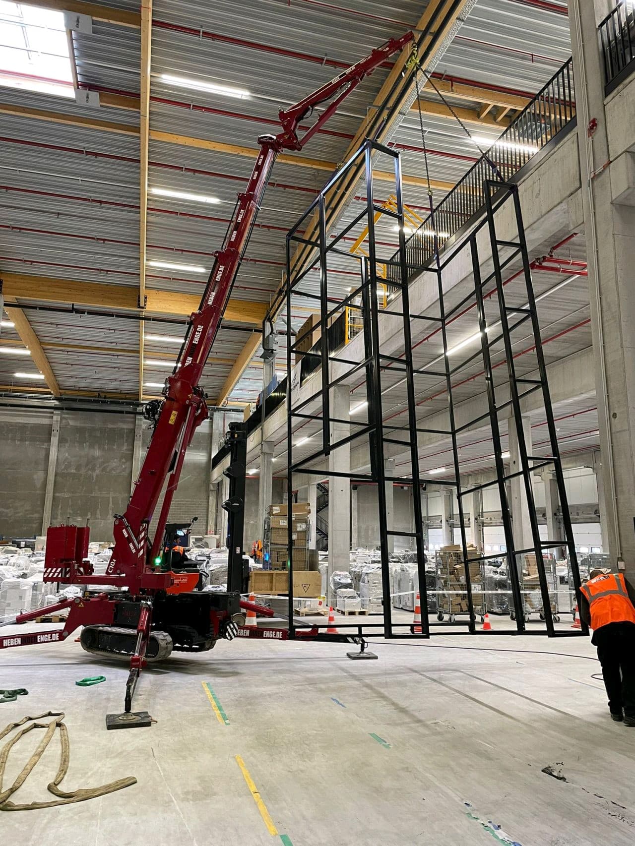 Hoeflon crane lifting a metal frame in a warehouse.